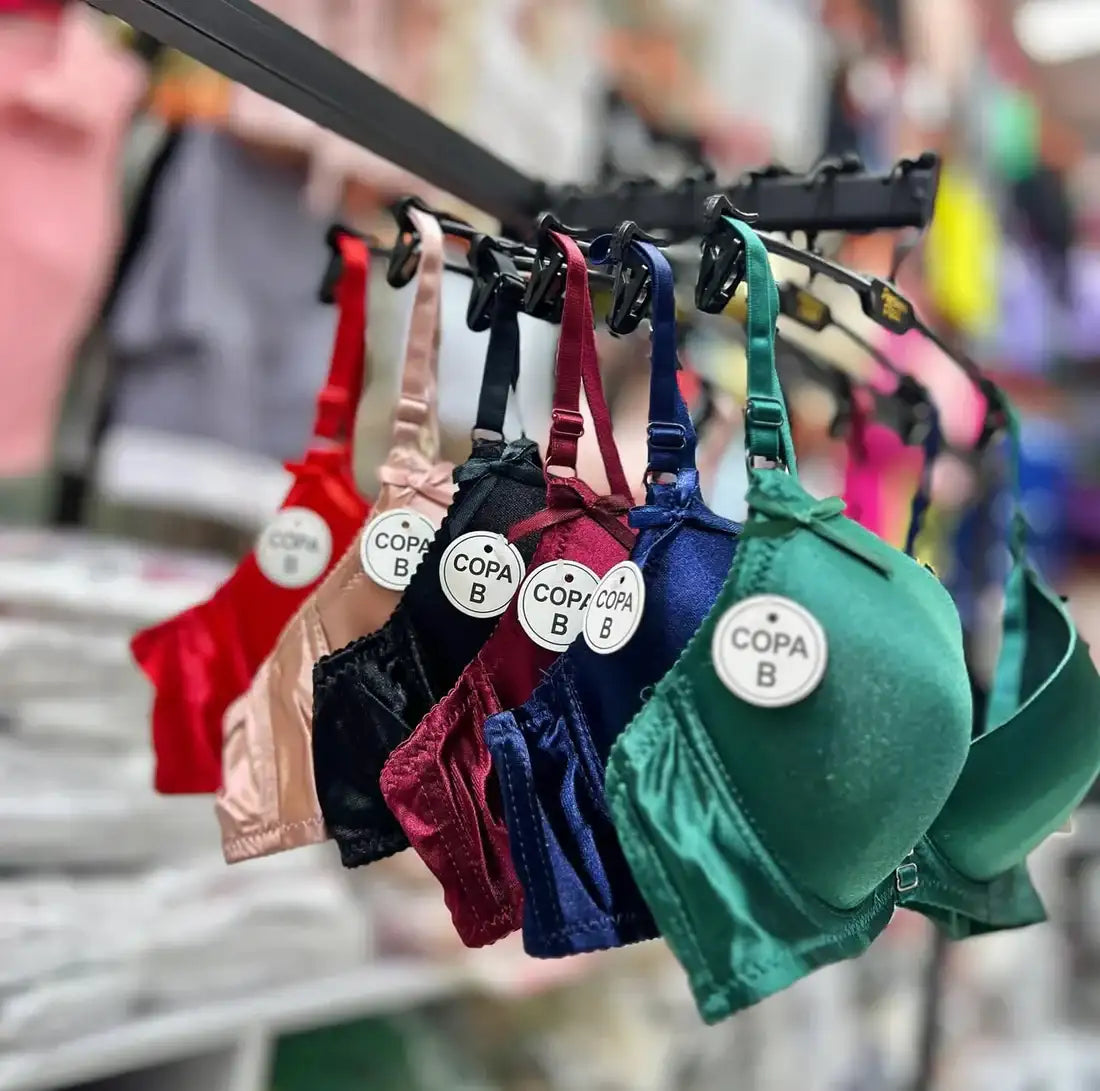 Colorful bras hanging on a rack with visible brand labels.