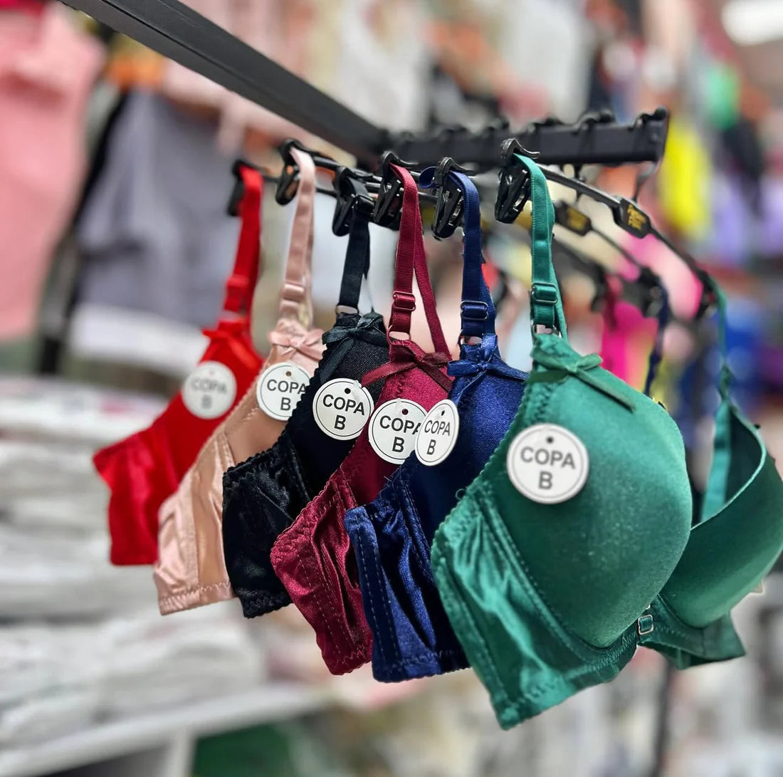 Colorful bras hanging on a rack with visible brand labels.