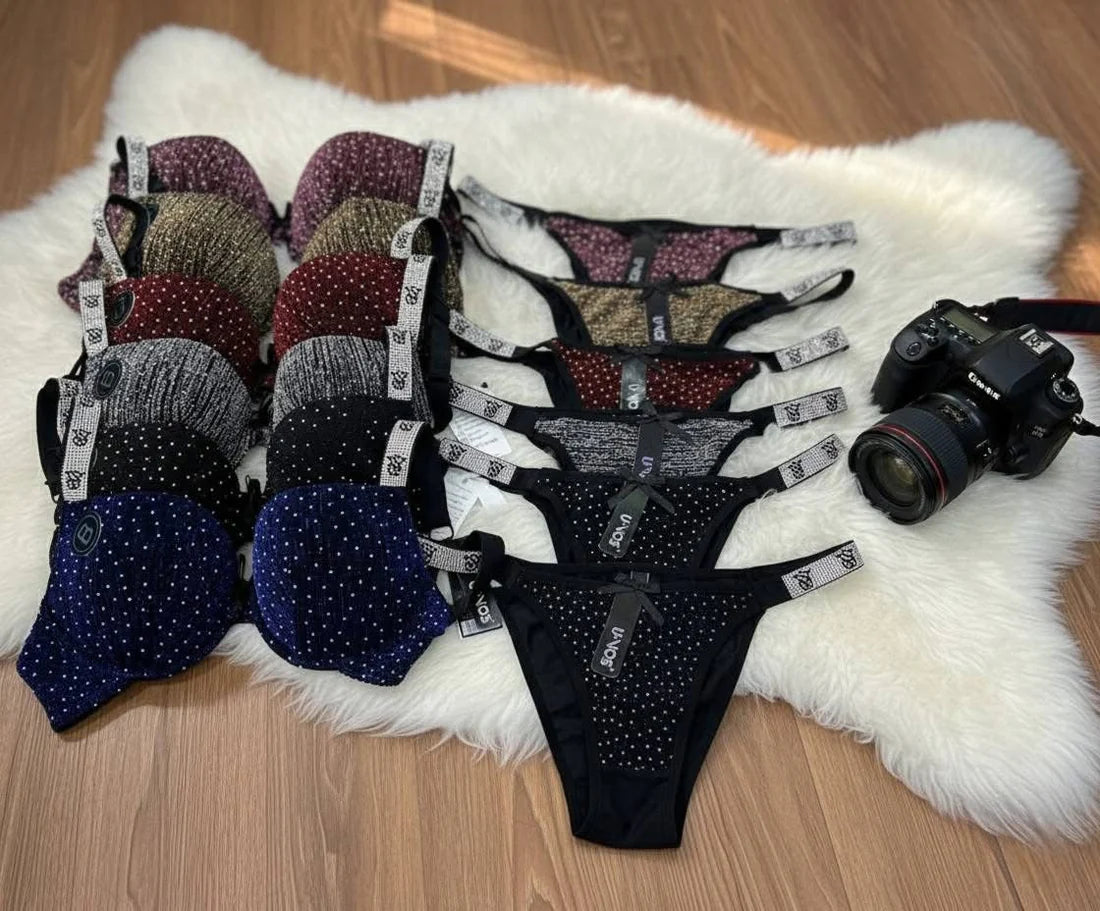 Collection of women's lingerie on a white fur rug with a camera.