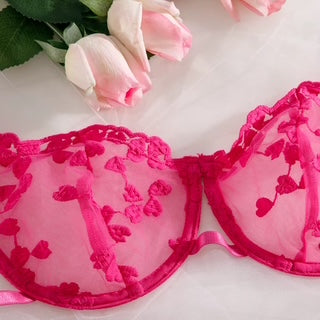 Pink bra with floral embroidery on a white background with pink roses.