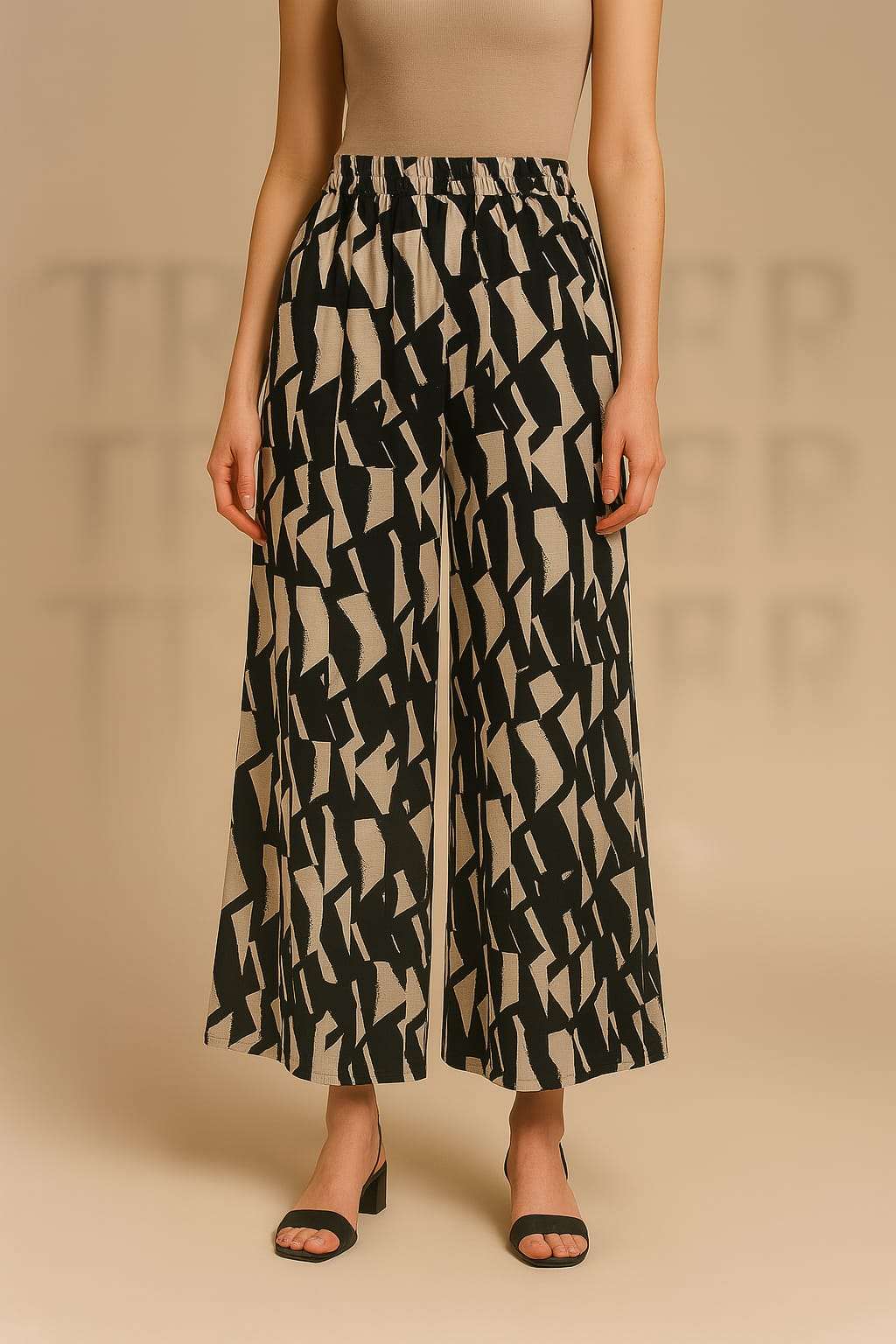 Person wearing a patterned black and beige wide-leg pants on a beige background
