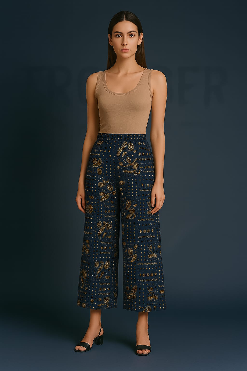 Woman wearing a beige tank top and dark patterned pants against a dark background
