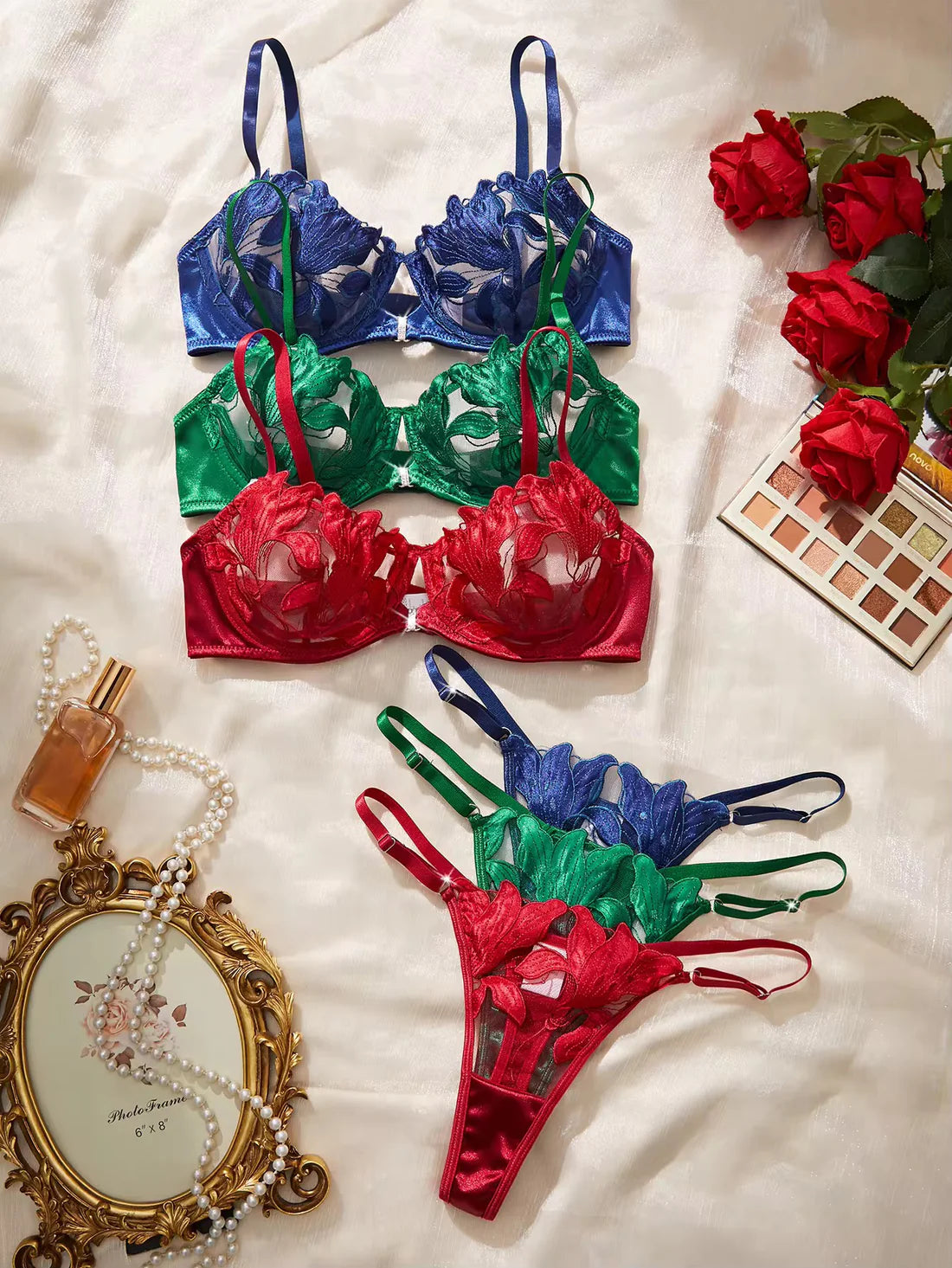 Set of colorful lingerie with a makeup palette and roses on a white background