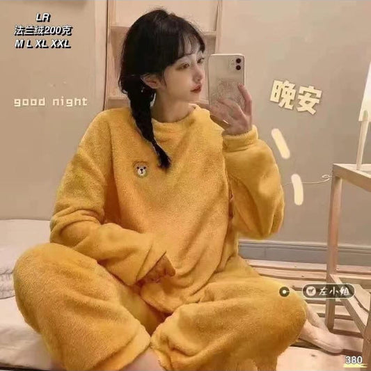 Person wearing yellow pajamas taking a mirror selfie in a room with text on the wall.