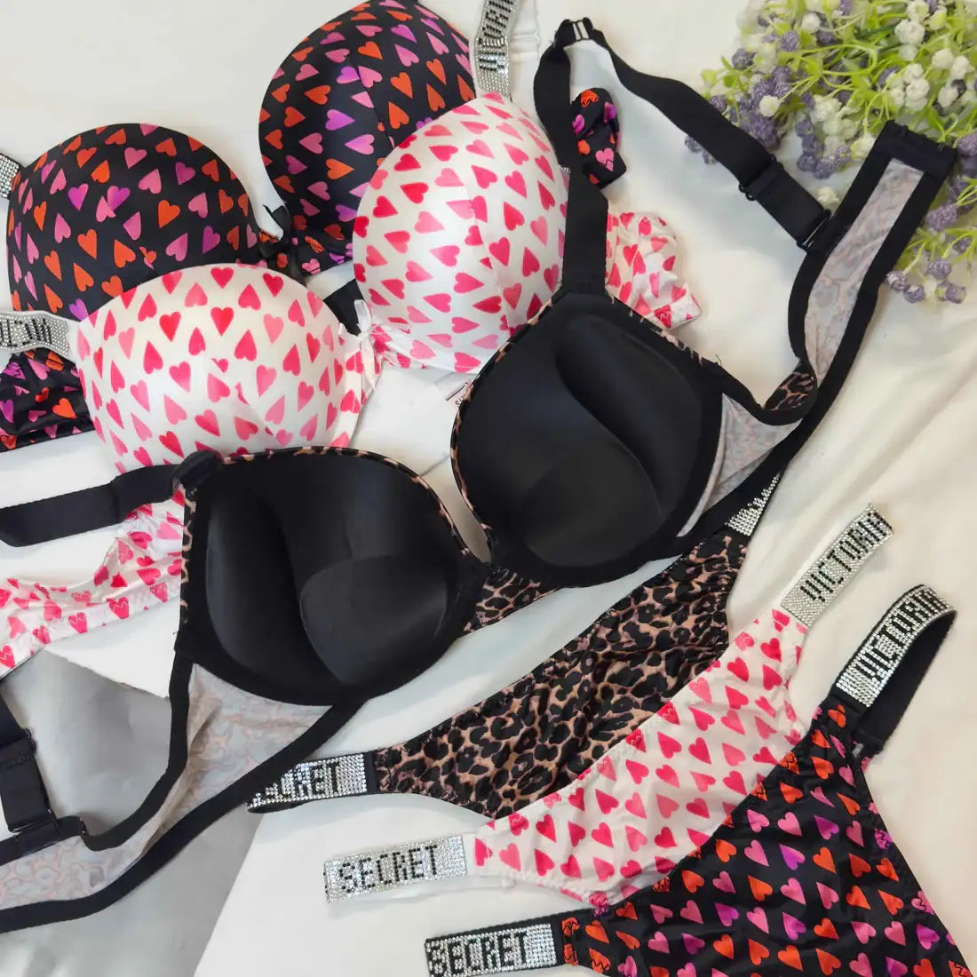 Black bra with heart patterns and leopard print on a white surface with flowers.