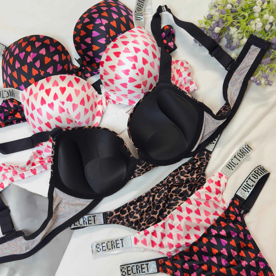 Black bra with heart patterns and leopard print on a white surface with flowers.