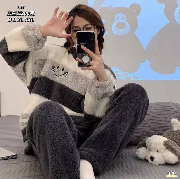Person wearing a striped sweater sitting on a couch with a teddy bear, taking a mirror selfie.