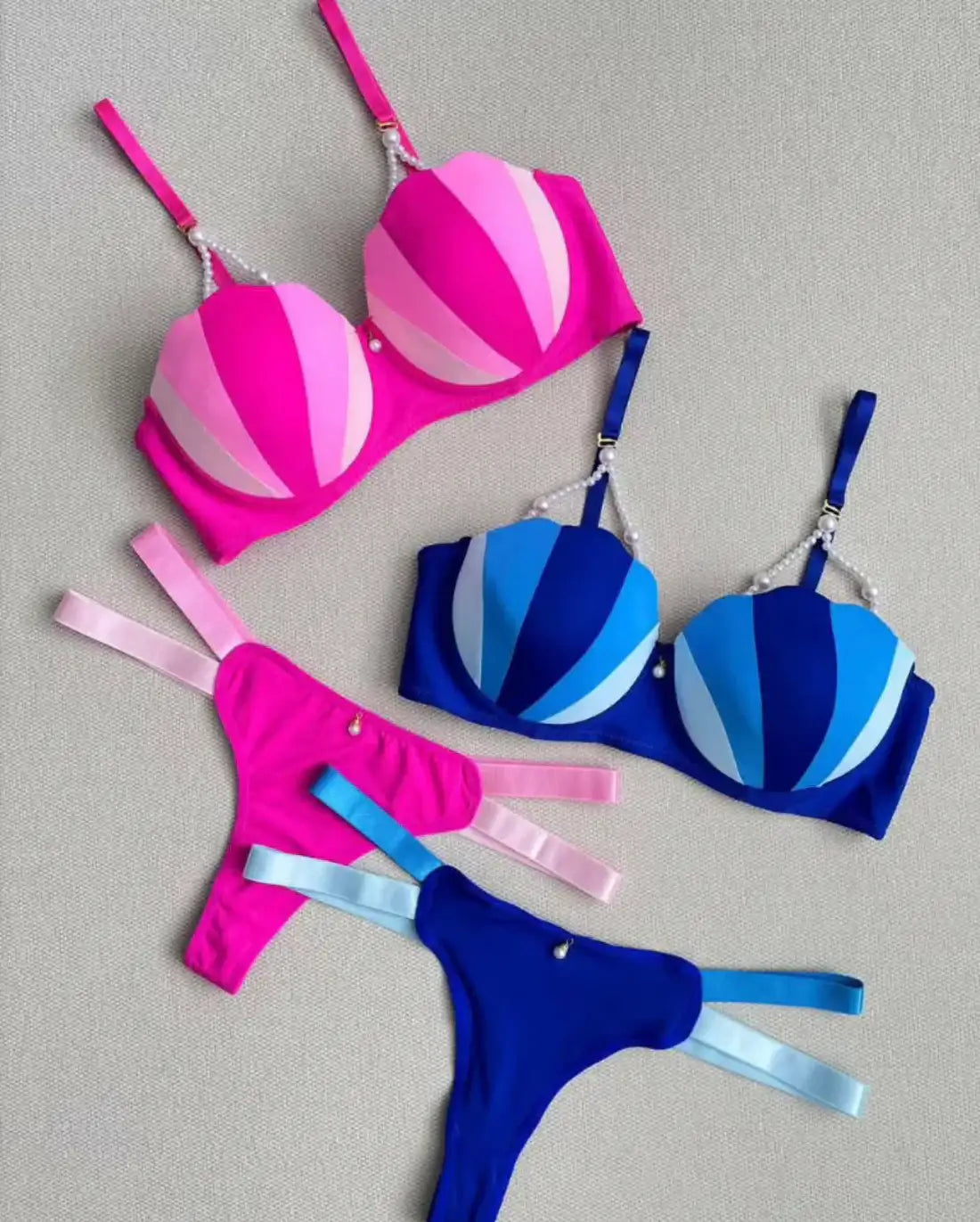 Pink and blue striped bikini set on a gray background