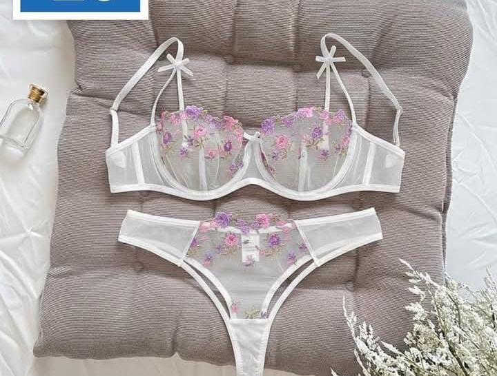 Floral lingerie set on a gray cushion with a bottle and flowers in the background