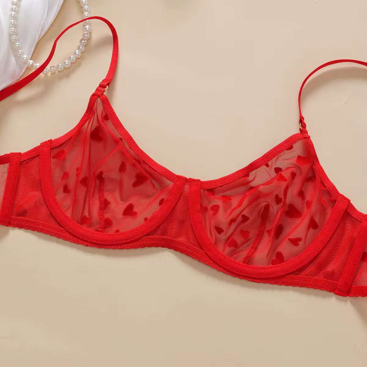 Red bra with heart cutouts on a beige background