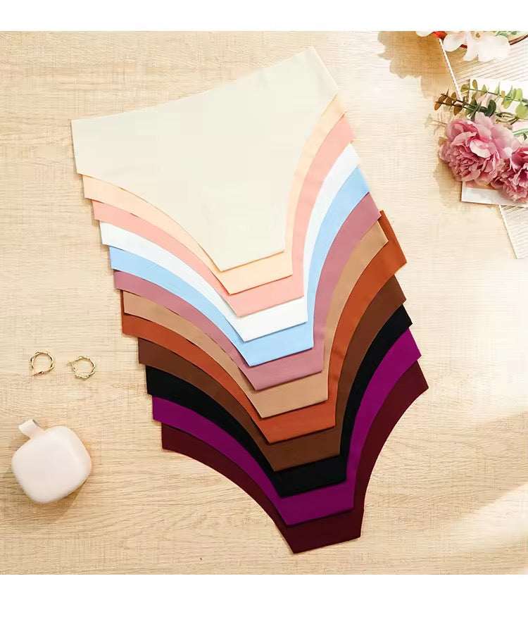 Stack of colorful fabric swatches on a wooden surface with a small white bag and pink flowers.