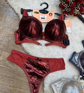 Red bra and panties set on a wooden floor with packaging and flowers in the background.