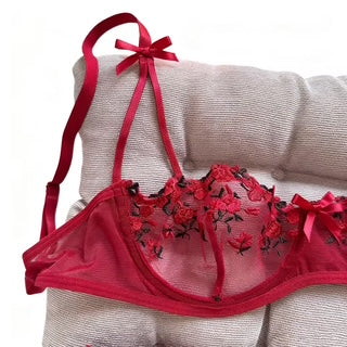 Red lingerie set with floral details and a bow on a beige surface