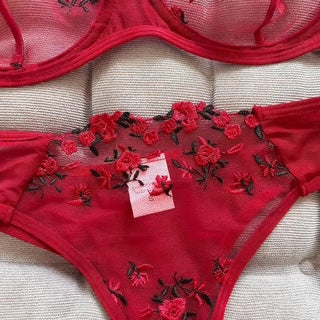 Red lingerie set with floral embroidery on a beige surface