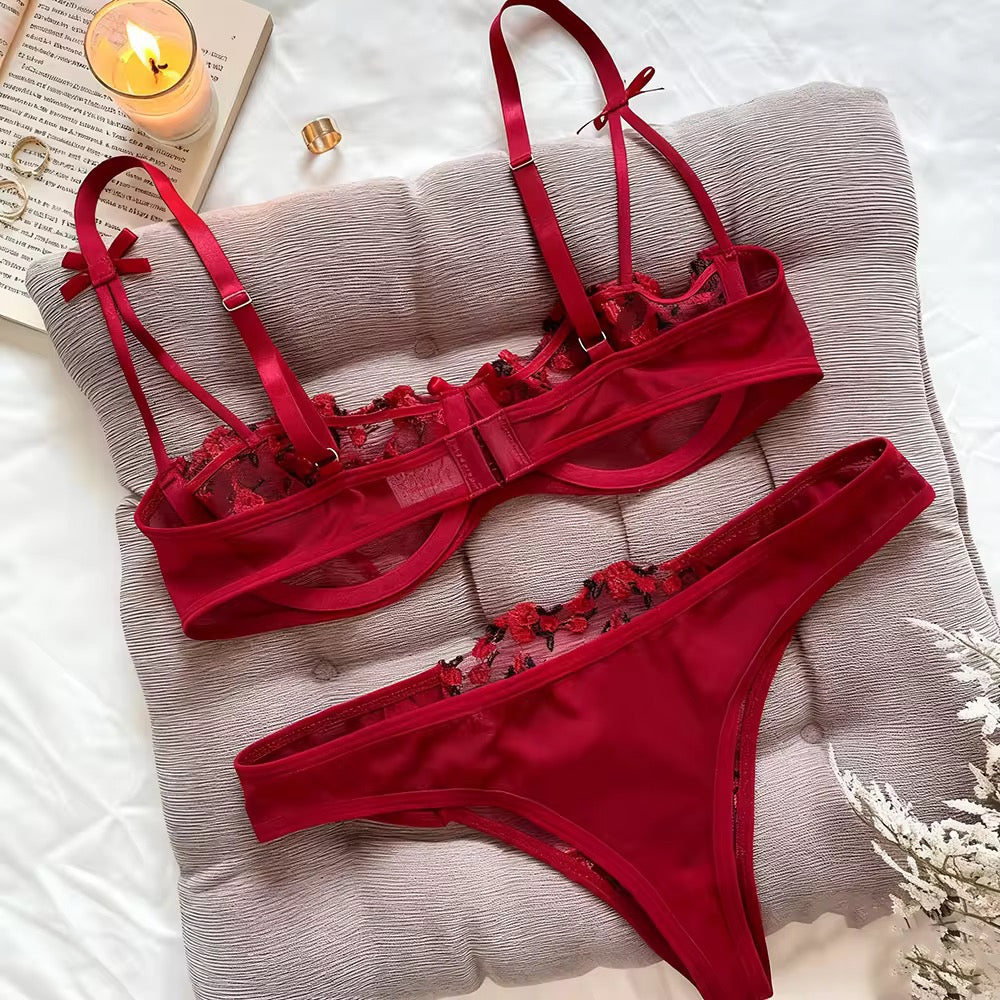 Red lingerie set with lace details on a textured surface.