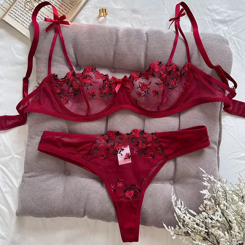 Red embroidered lingerie set on a gray cushion with a white background