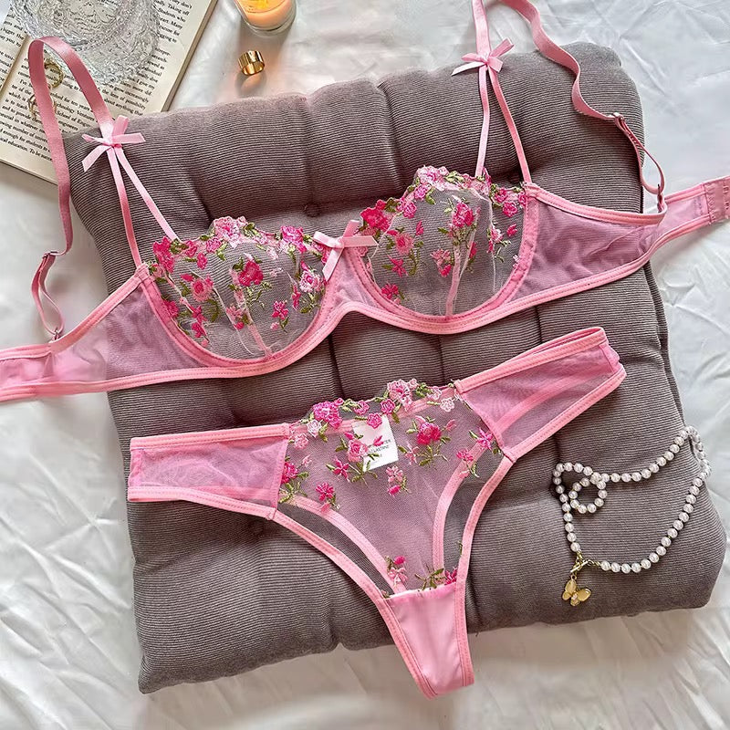 Pink floral lingerie set on a gray pillow with a white background