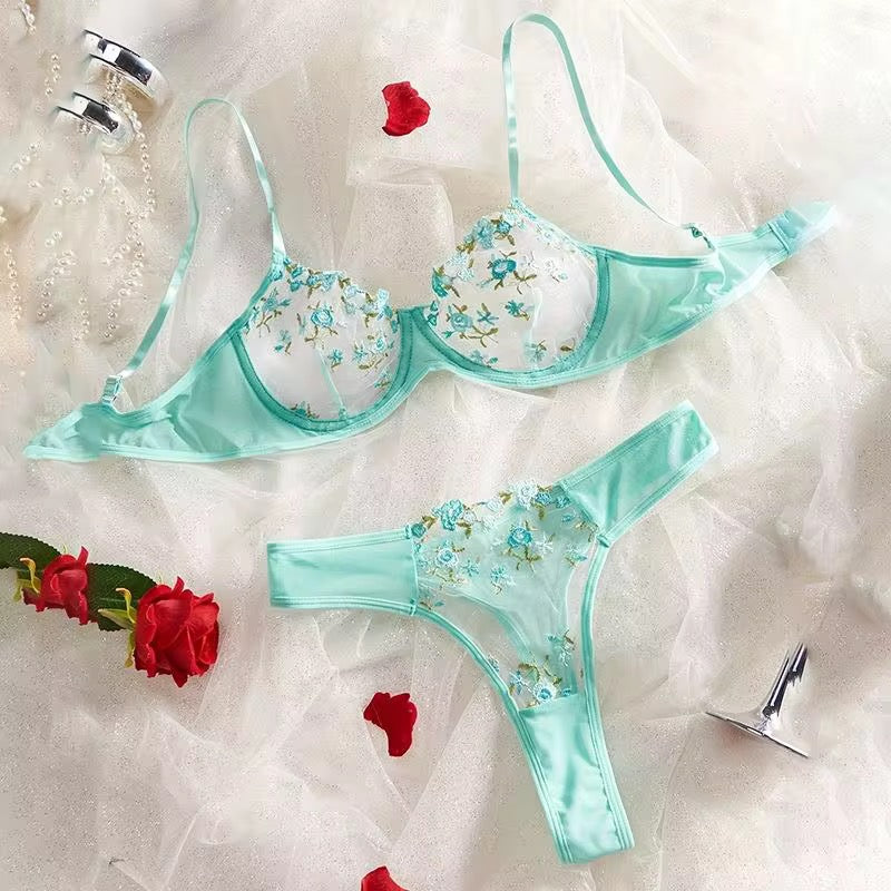 Teal lingerie set with floral design on a textured white background with red flowers.
