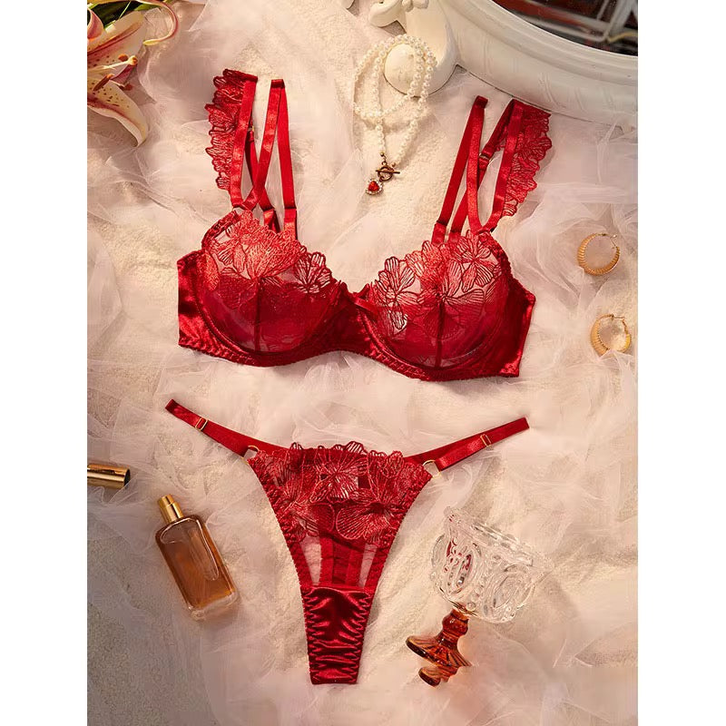 Red lace lingerie set on a textured surface with decorative items.
