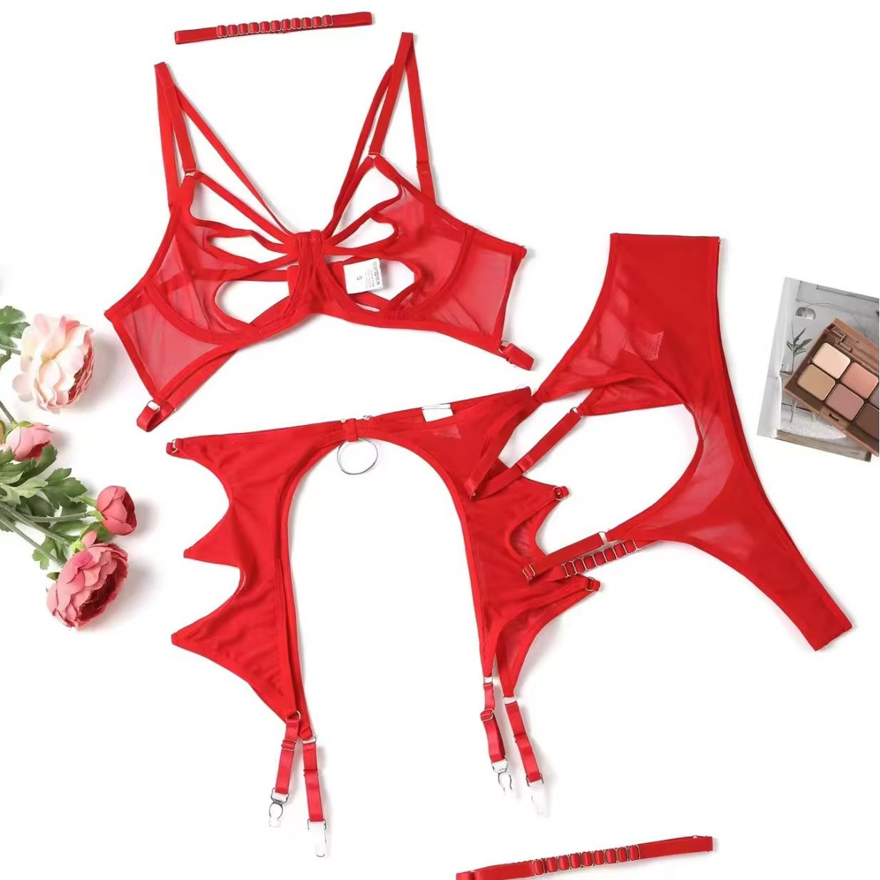Red lingerie set with floral and makeup products on a white background