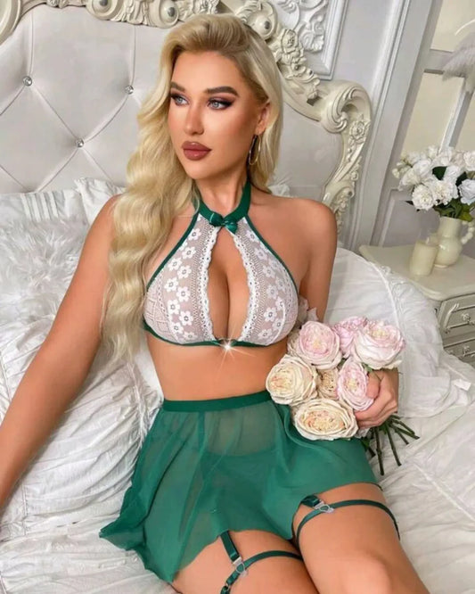 Woman in a green lace outfit holding flowers on a bed