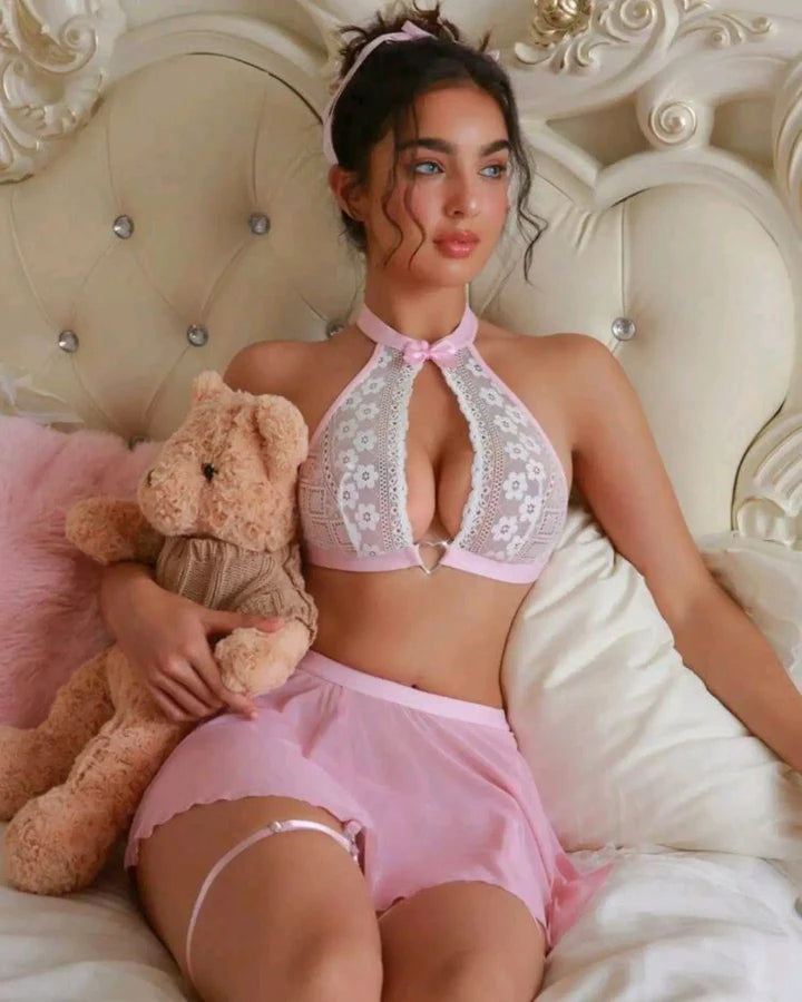 Woman in pink lingerie holding a teddy bear on a decorative couch