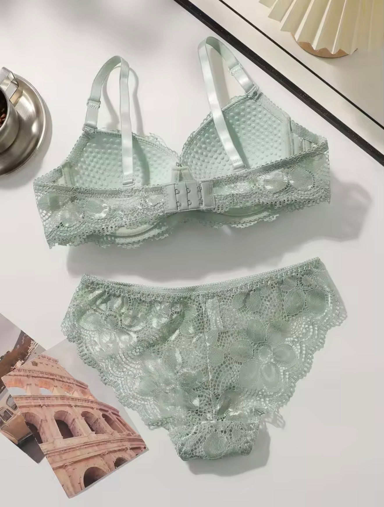 Green lace bra and panties set on a white surface with architectural magazine page.