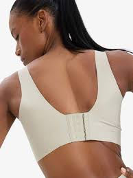A close-up back view of a model wearing a beige sports bra with a center back strap and hook-and-loop closure.