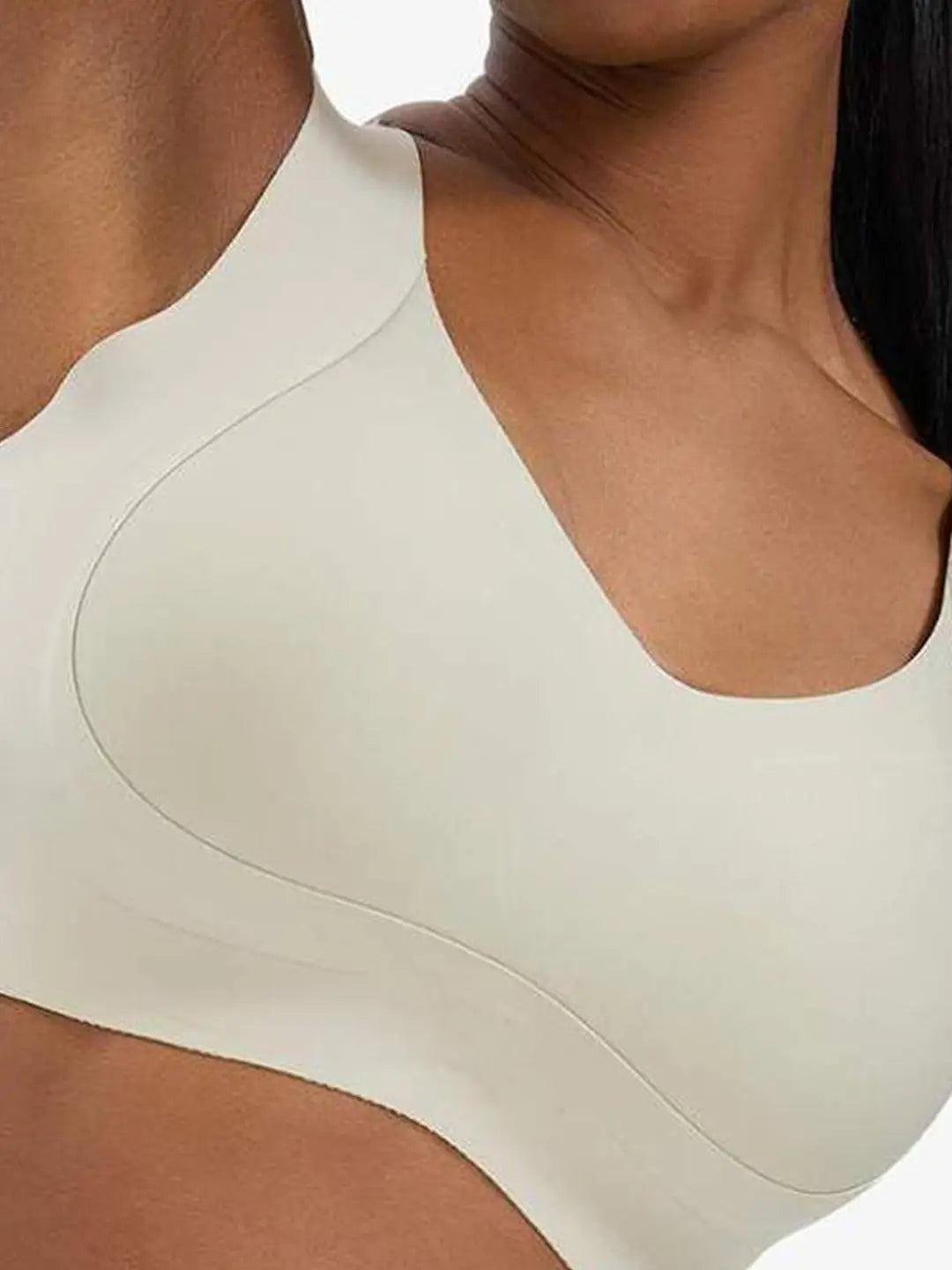 Close-up of a woman wearing a seamless, wide-shoulder sports bra in a light cream or off-white color.