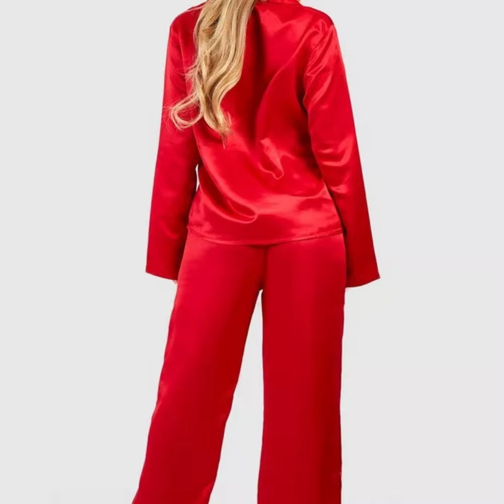 A woman wearing a bright red satin two-piece set, shown from the back against a light gray studio background.