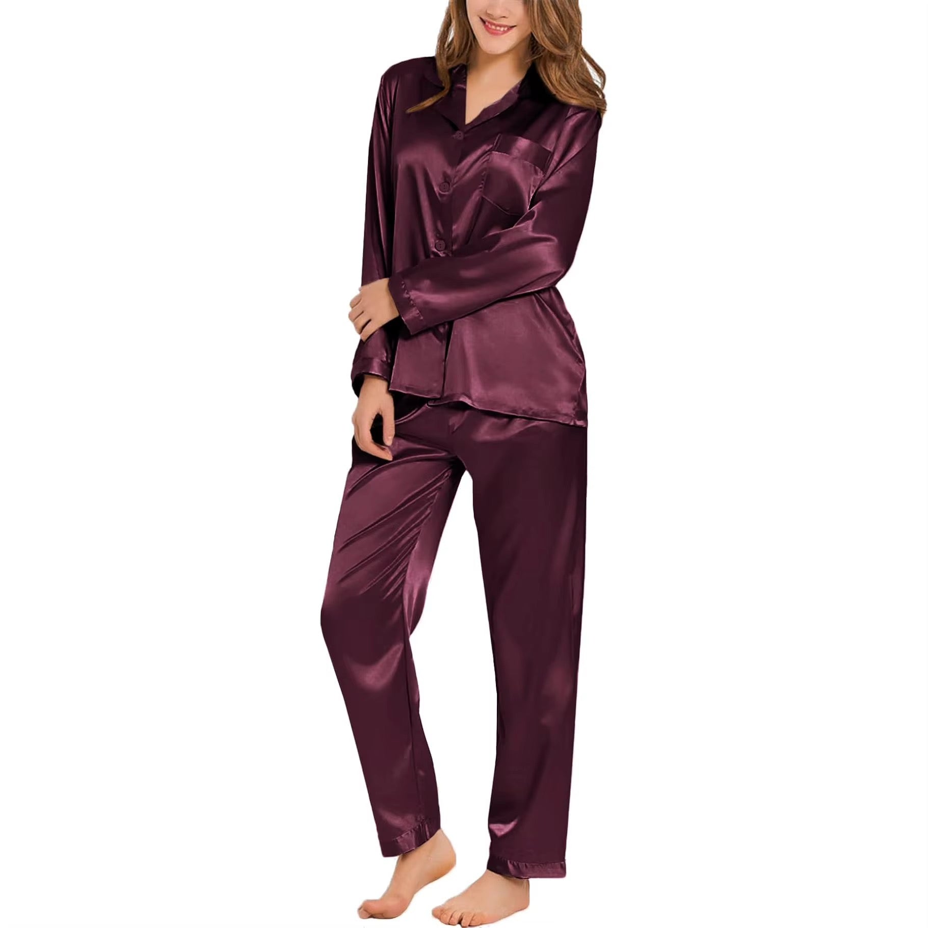 A woman modeling a two-piece satin pajama set in a deep plum purple color, featuring a long-sleeve collared top and matching pants, set against a plain white background.