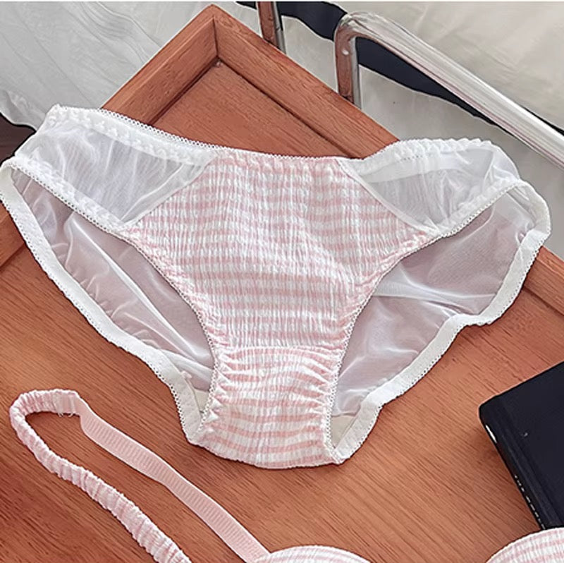 Pink and white gingham patterned underwear with sheer white mesh side panels and white lace trim, laid flat on a wooden surface.