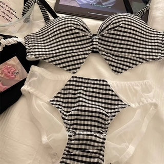 A three-piece bikini set laid flat on a white surface. The set features a black and white gingham check pattern on the bandeau-style top and matching bottoms, with sheer white mesh undergarments.
