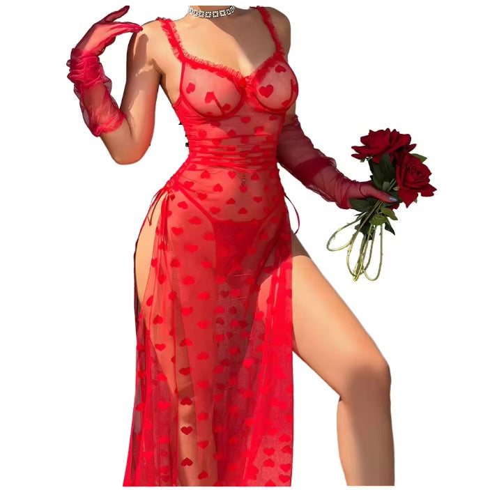 A woman models a sheer red lingerie dress with a heart pattern, matching red gloves, and holds a bouquet of red roses against a plain white background.