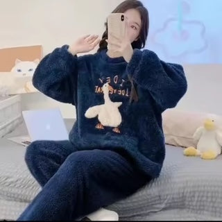 Person wearing a dark blue fleece outfit with a cartoon design, sitting on a bed.