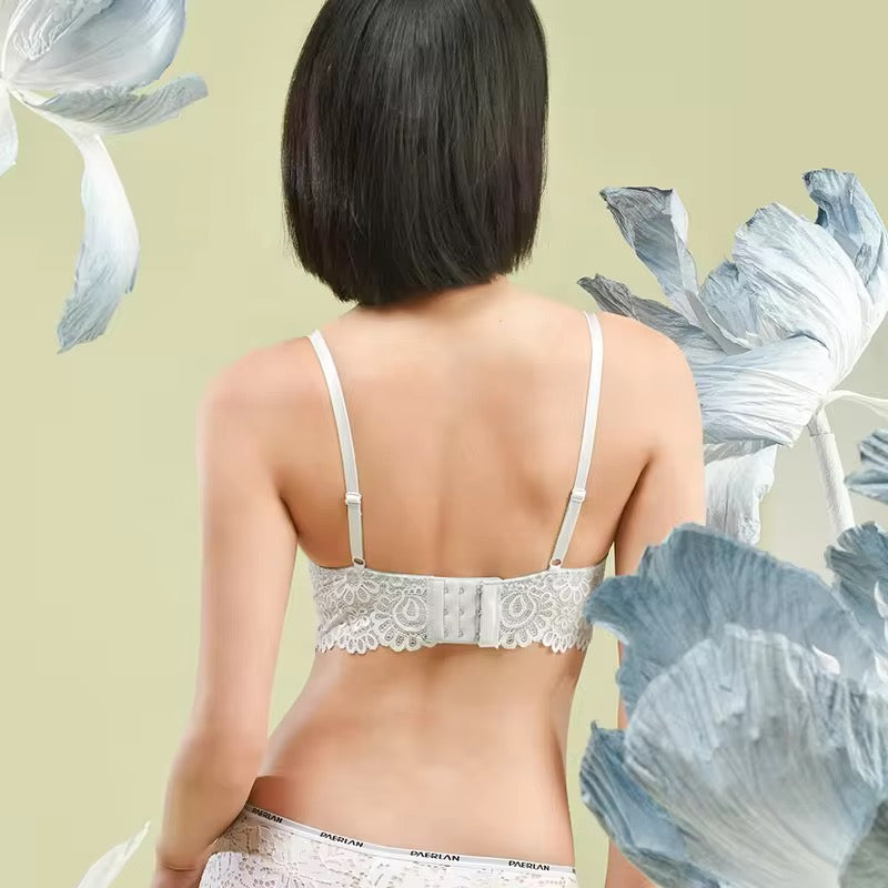 Woman wearing a white lace bralette with floral decorations on a light green background