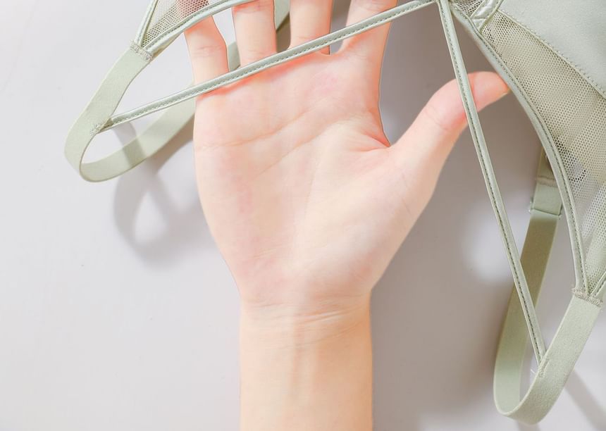 Hand holding a transparent green mesh fabric against a light background