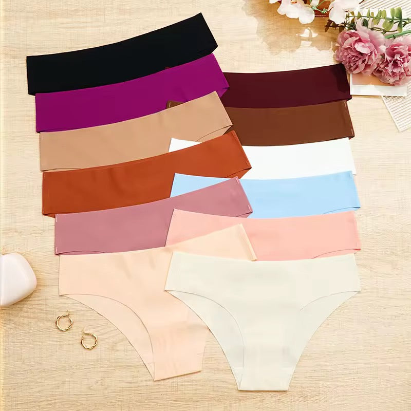 Collection of colorful underwear on a wooden surface with flowers and jewelry.
