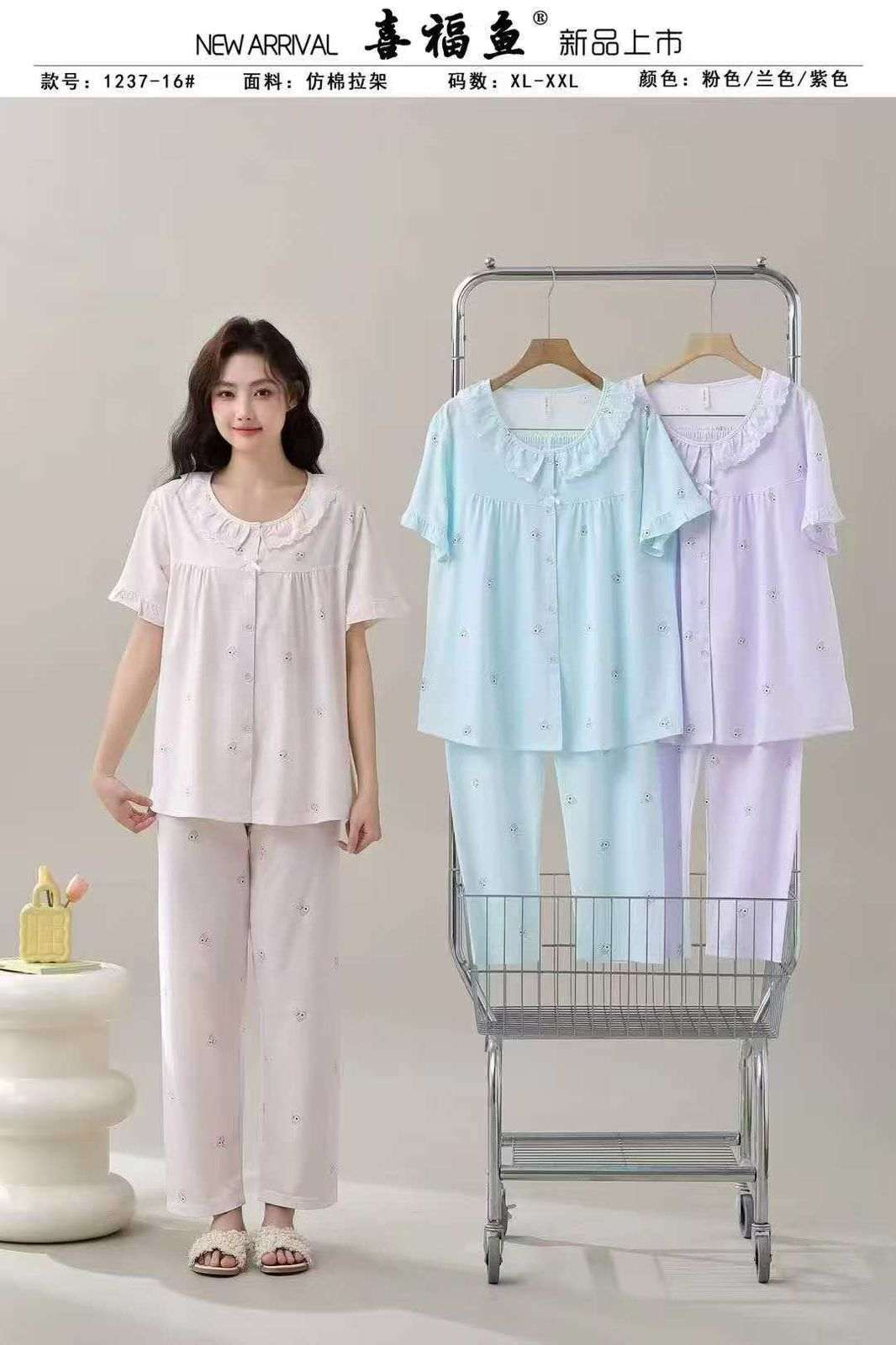 Woman wearing a light pink pajama set with two additional sets displayed on a cart.