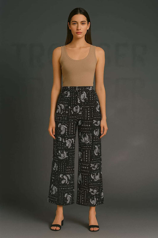 Woman wearing a beige tank top and black patterned pants on a gray background