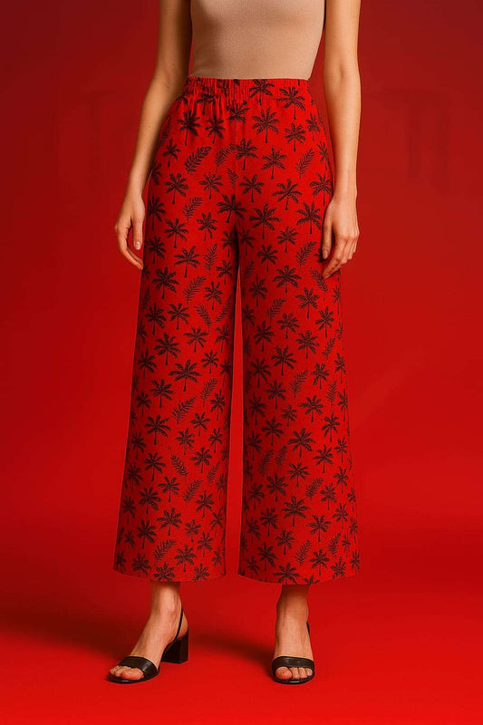 Red pants with black floral pattern worn by a person on a red background