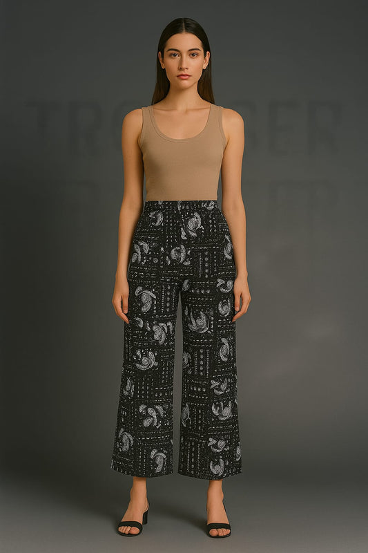 Woman wearing a beige tank top and black patterned pants on a gray background