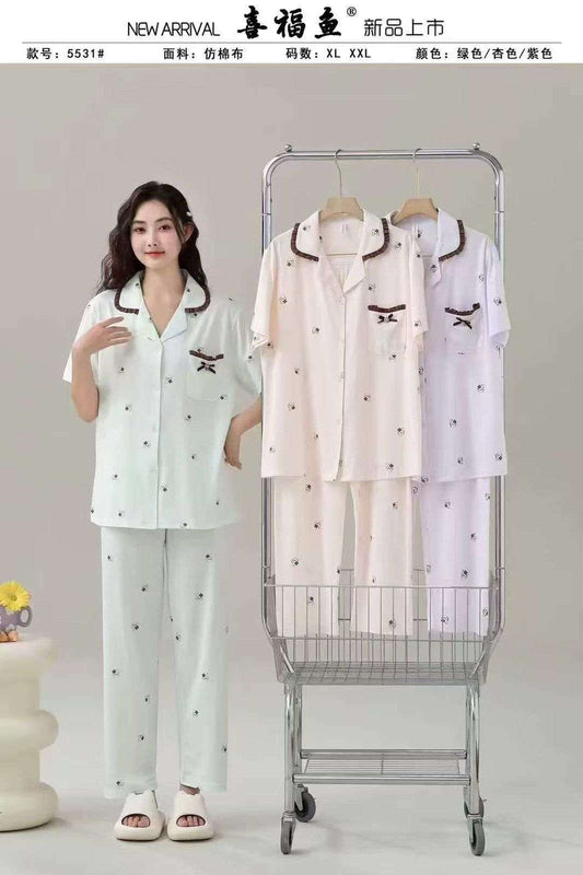 Woman wearing a pajama set next to a shopping cart with more pajama sets on it, against a plain background.