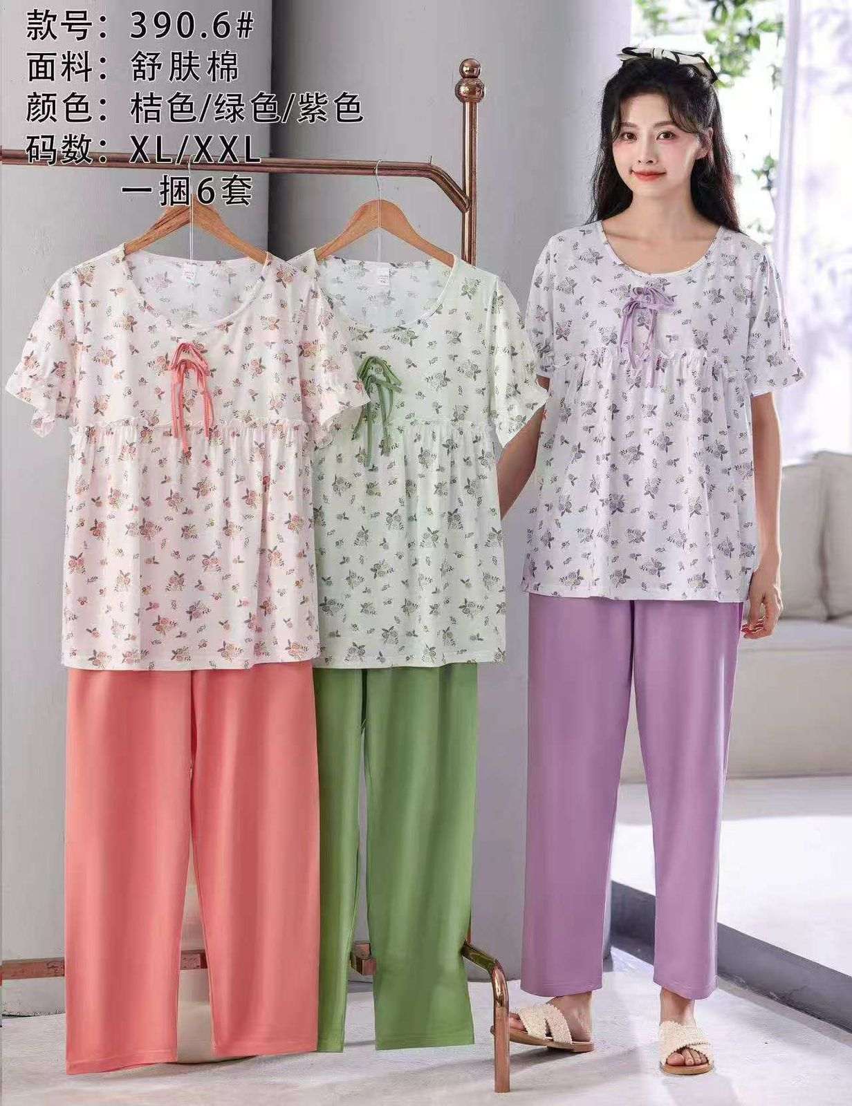 Woman wearing a floral pajama set with three other sets displayed on hangers.