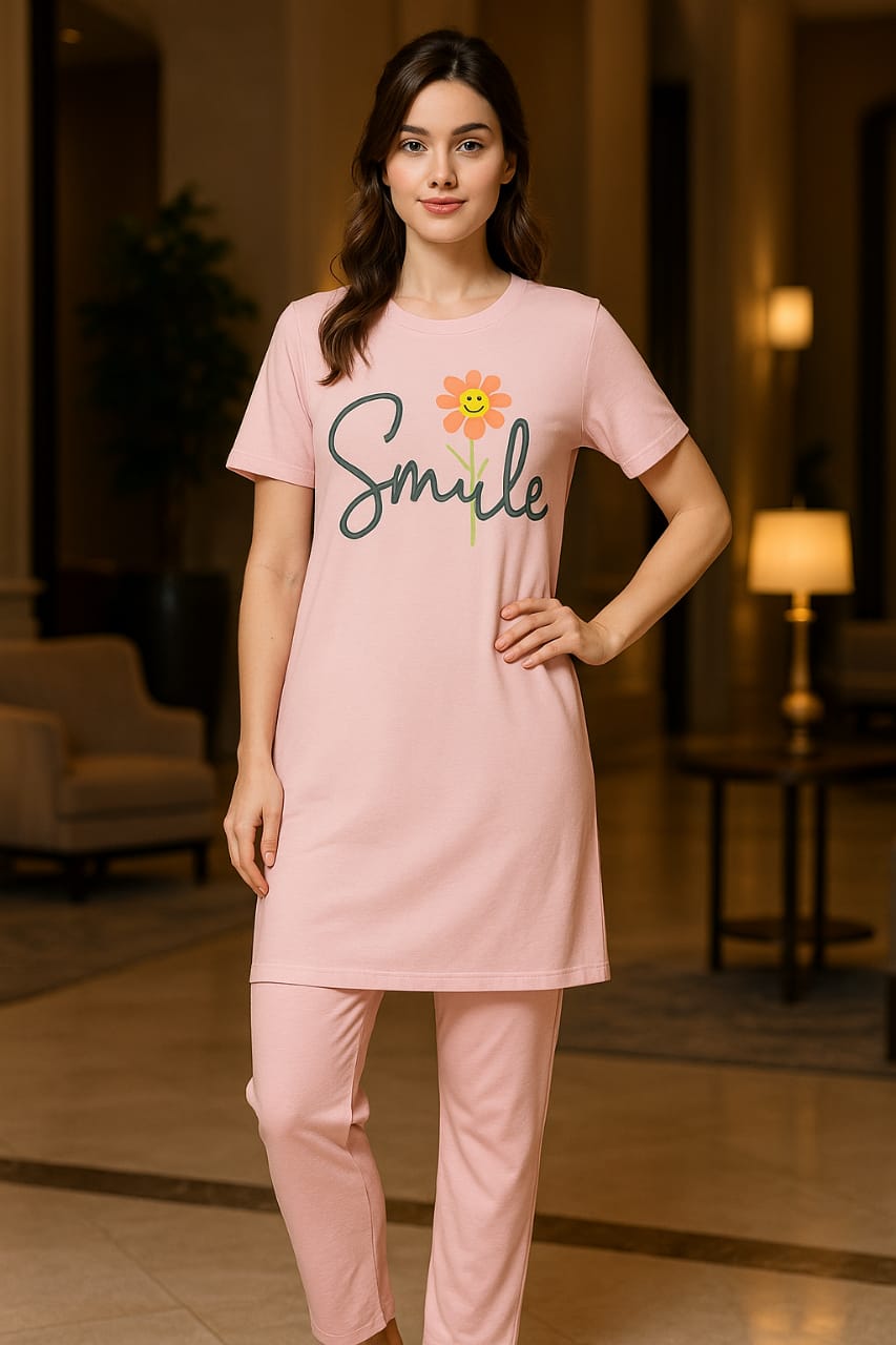 Woman wearing a pink pajama set with 'Smile' and flower design in a room.