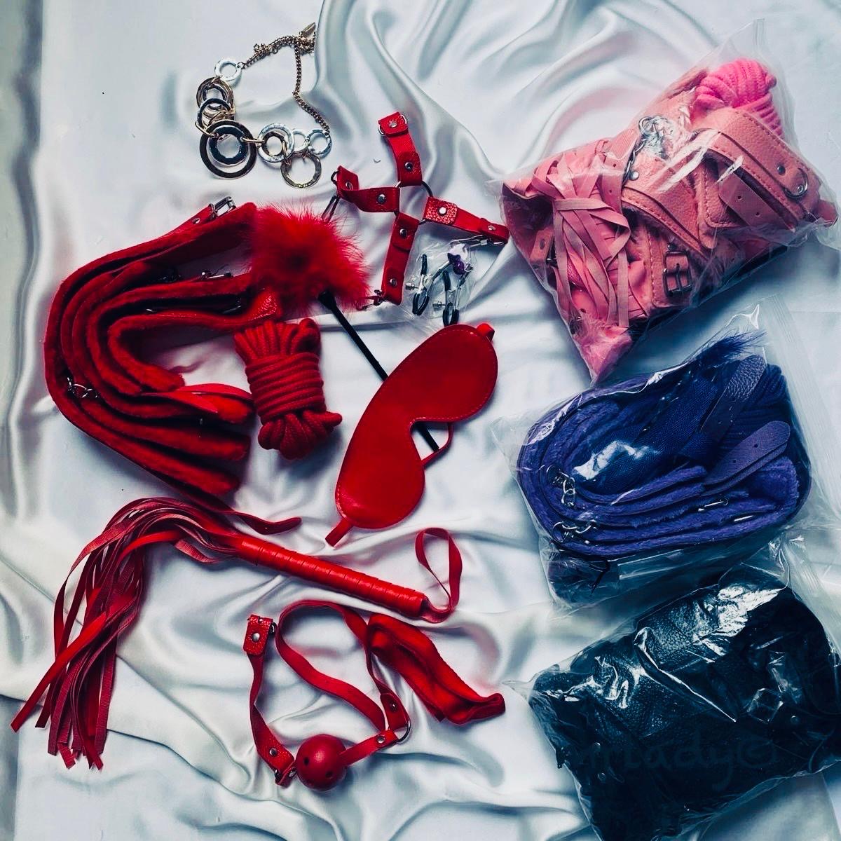 Collection of red and blue bondage accessories on a white fabric background